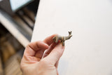 A vintage African mini elephant with a dark patina held to demonstrate its scale.