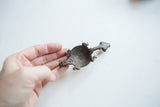 Vintage African turtle pendant with a dark, aged patina held in hand for scale.