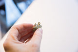 A hand holds the vintage oxidized turtle pendant, highlighting its small size and texture.