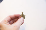 Side view of the vintage turtle pendant held in hand, showing its scale and oxidized finish.