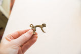 Vintage bronze monkey pendant held to show its profile and scale.