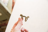 Side profile of the small vintage African bronze monkey pendant held in hand.