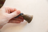 Hand holding the small vintage African bronze bell to show scale and texture.