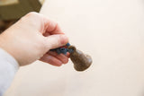 Hand holding the small vintage African bronze bell to illustrate its scale.