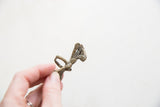 Vintage African bronze ring held to display its sculptural peacock design and aged texture.