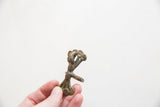 A hand holding the vintage African bronze ring, showing its profile and textural patina.