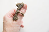 Vintage African bronze peacock ring viewed from the side on a thumb.