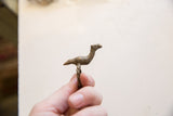 Profile view of the stylized camel figure atop a twisted bronze band.