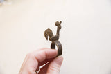 Profile view of a vintage African bronze ring highlighting the rooster's textured form.