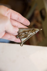 Vintage African bronze pendant held in hand, revealing its warm patina and texture.