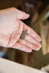 Small vintage African bronze pineapple pendant held in a hand for scale.