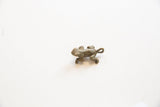 Side profile of the bronze frog pendant, showing its aged texture and curled tail.