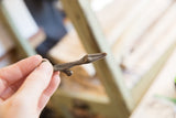 The smooth, aged patina of the abstract bronze lizard pendant held in hand.