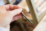 Vintage African bronze lizard pendant held in hand showing its smooth, sculptural form.
