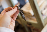 Vintage handmade bronze lizard pendant held in hand to show its smooth, twisted form.