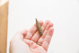 Vintage African bronze long face pendant held in hand for scale.