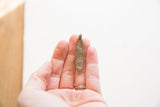 Vintage African bronze pendant resting in a hand to show scale and aged texture.