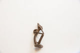 The aged bronze texture and curved profile of the vintage thinking man pendant.