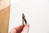 Vintage African bronze man pendant held in hand to show its scale.