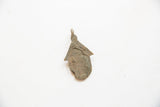 Reverse side of a vintage African bronze hut pendant showing its rustic, aged texture.