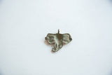 The reverse side of a vintage elephant pendant with a weathered bronze patina.