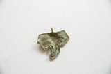 Aged green patina on the textured, concave back of the bronze elephant pendant.