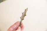 A hand holds the vintage bronze lizard, showing its scale and aged, textured surface.