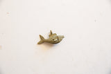 Side view of a vintage bronze fish pendant showing incised details and an aged patina.