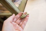 Vintage African bronze fish pendant held in a hand to show its scale and texture.