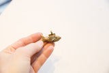 Small vintage African bronze fish pendant showing its scale and lattice texture.