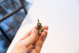 Vintage African monkey sitting pendant held in hand to demonstrate its small size.