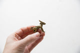 Small vintage African impala ram pendant with an aged patina held in hand.