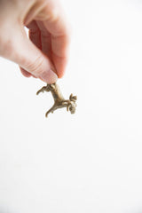 Vintage African impala ram pendant, held, showing textured body and curved horns.