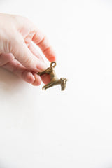 Vintage African impala pendant with a weathered patina held to show its small scale.