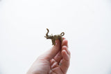 Vintage bronze elephant pendant held in hand to show its small size and texture.