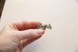 Vintage African iguana pendant with an oxidized finish, held to show scale.