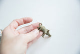 Vintage African bronze boar pendant held in hand, showing its aged patina and scale.