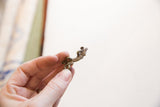 Vintage African bronze iguana pendant held in hand to show scale.