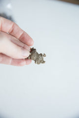 The petite scale of the vintage bronze armadillo pendant shown in hand.