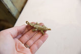 Vintage African bronze crocodile pendant with aged patina and detailed texture, held in hand.