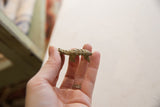 Vintage bronze pangolin pendant held in hand, showing its size and detailed texture.