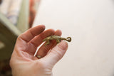 Small African bronze pangolin pendant held in hand, showing its size and vintage texture.