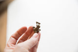 Vintage African bronze frog pendant held in hand, showing its petite scale and textured surface.