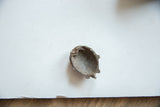 A view of the hollow interior of the vintage bronze face collectible, showing aged, rustic texture.