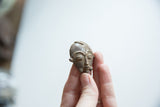 Angled perspective of the small African bronze child's face showing its aged patina.