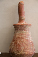 Earthen patina and handmade ridges on the shoulder of an antique pottery vase.