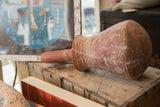 Antique North African pottery vase resting on its side, showing a weathered red finish.