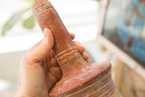 The aged surface and handmade texture of a North African red slip ware vase held in hand.