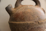 Close-up of the antique vase's earthy red slip patina and impressed band.
