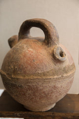 The rustic handle, textured patina, and side spout of an antique North African vase.